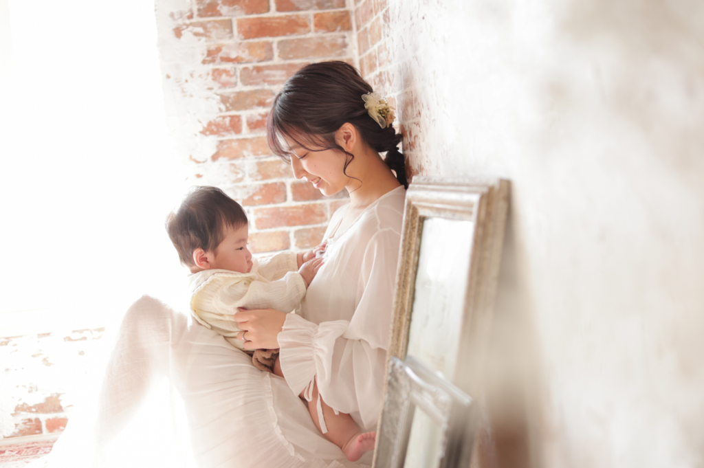 ママが赤ちゃんを膝に抱えて微笑んでいる